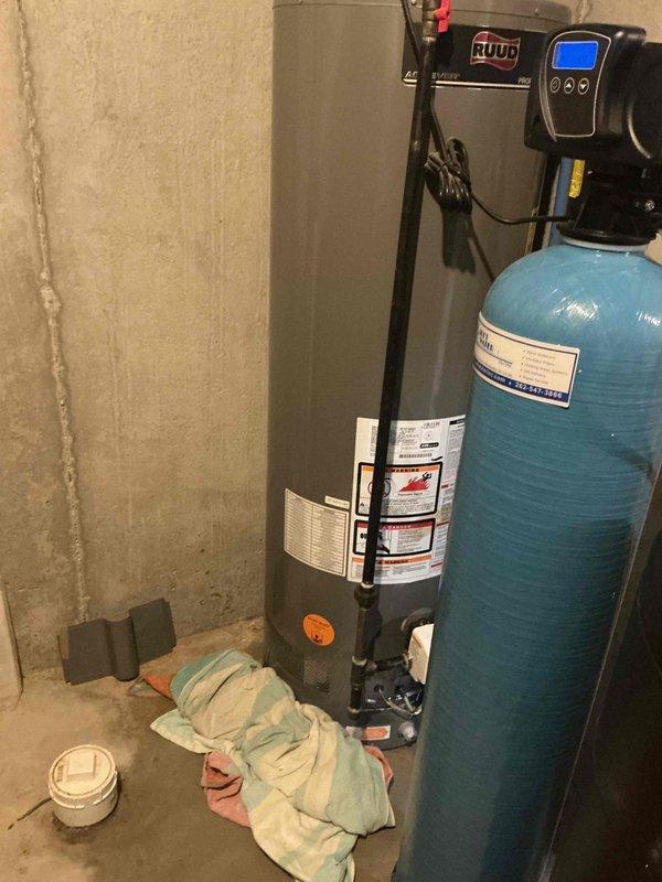 Inspected Ruud tanked water heater system and adjacent water filtration equipment in basement utility area. Performed routine maintenance on water heater, checking connections and verifying proper operation of temperature and pressure relief valve. Confirmed water treatment system with digital control head was functioning correctly and properly integrated with the water heater setup.