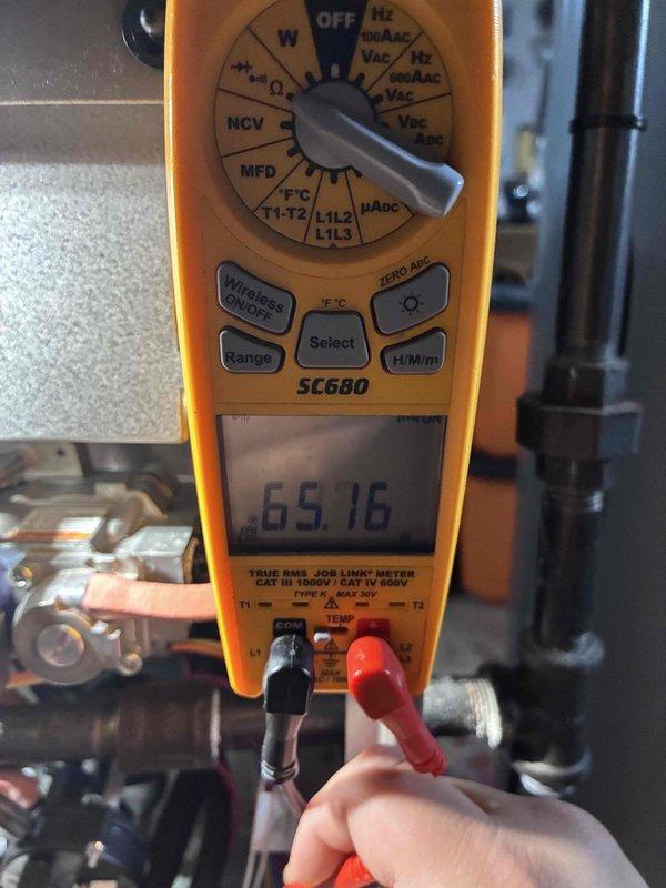 Performed comprehensive tune-up on aging HVAC system, including voltage testing with SC680 multimeter (reading 65.16V) and mechanical adjustments using hex key. Identified and documented significant corrosion and rust on internal components, particularly on metal bracket assembly, and noted proper wire securing with zip ties though system shows signs of wear requiring future attention.