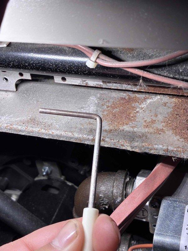 Performed comprehensive tune-up on aging HVAC system, including voltage testing with SC680 multimeter (reading 65.16V) and mechanical adjustments using hex key. Identified and documented significant corrosion and rust on internal components, particularly on metal bracket assembly, and noted proper wire securing with zip ties though system shows signs of wear requiring future attention.