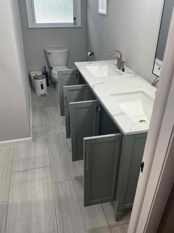 Completed installation of new bathroom vanity with integrated sink and faucet. Connected supply lines and drain assembly with PVC trap. Ensured proper alignment and verified no leaks after installation.