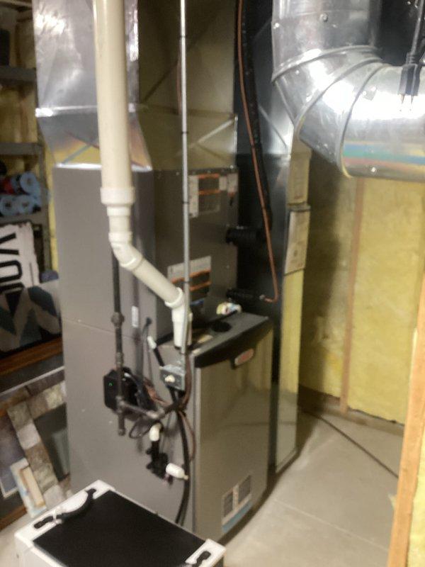 Successfully completed installation of new HVAC system in residential basement, including gray furnace unit with proper ductwork connections and white PVC drainage/ventilation piping. System includes A/C and coil components with all electrical connections properly secured and tested for optimal performance.