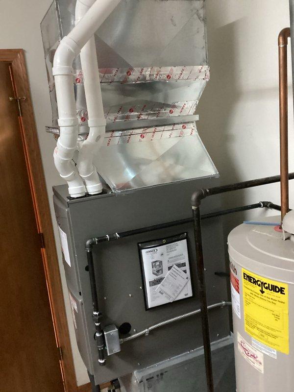 Completed installation of a new furnace system in the utility area, connecting the unit to existing ductwork with PVC venting. Properly secured all components, including the metal ductwork and PVC pipe connections, and verified proper clearance between the furnace and adjacent water heater.