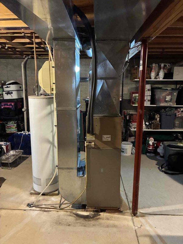 Conducted comprehensive inspection of existing HVAC system in basement utility room, including furnace unit with metallic ductwork, adjacent water heater, and electrical connections to the home's circuit breaker panel. Documented current system configuration and electrical service panel with properly labeled circuits for future replacement reference.