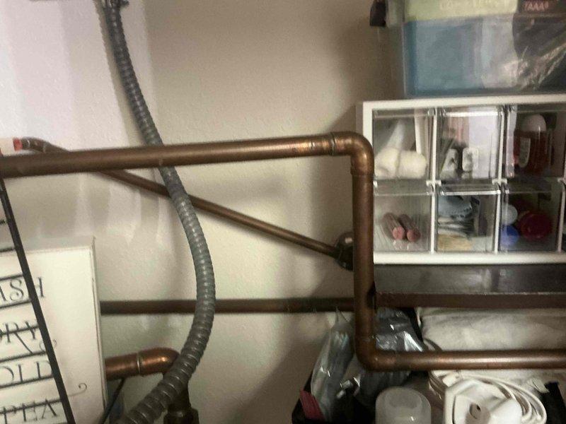 Conducted assessment of existing copper piping system in utility area, documenting condition of aged pipes with visible patina and existing connections. Evaluated integration requirements for replacement components with current plumbing infrastructure, including connection points for flexible conduit and protective cage installation needed for safety compliance.
