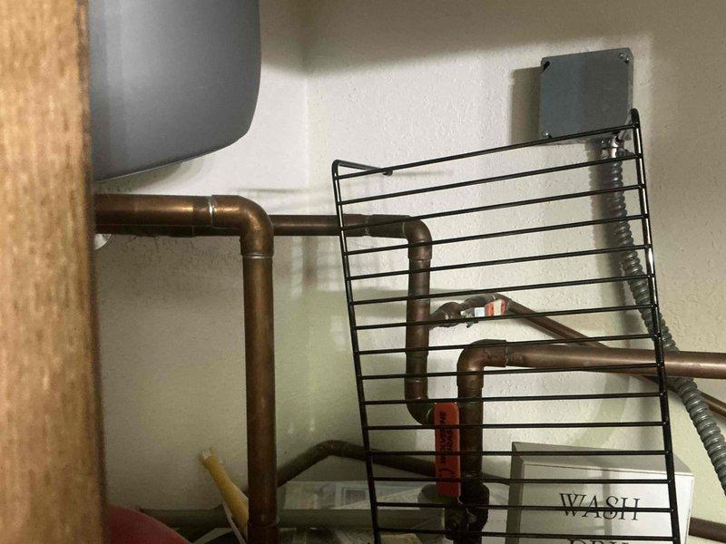 Conducted assessment of existing copper piping system in utility area, documenting condition of aged pipes with visible patina and existing connections. Evaluated integration requirements for replacement components with current plumbing infrastructure, including connection points for flexible conduit and protective cage installation needed for safety compliance.