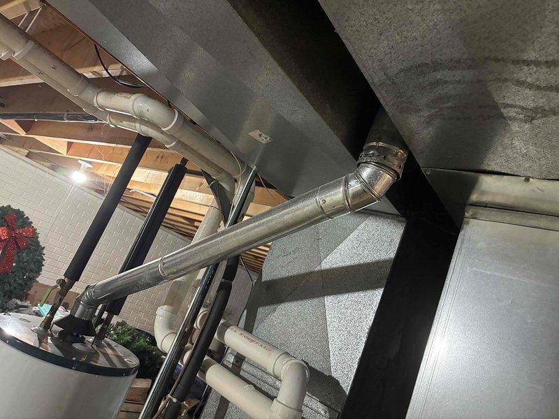Conducted assessment of existing HVAC system in basement utility area, documenting aging Carrier furnace unit with visible wear and associated ductwork condition. Recommended full system replacement due to efficiency concerns and observed discoloration on adjacent water heater indicating possible ventilation issues.