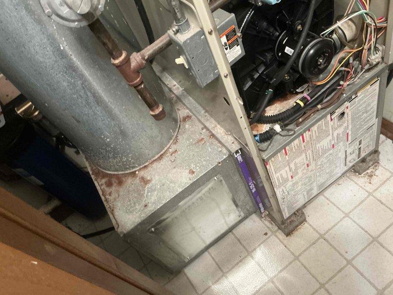 Performed assessment of existing HVAC system showing significant age-related deterioration, including visible corrosion on the housing and worn mechanical components. Recommended full system replacement with new air handler installation, complete with proper ductwork connections and PVC condensate drainage lines. Existing unit's blower assembly and belt system to be replaced with more efficient modern equipment.