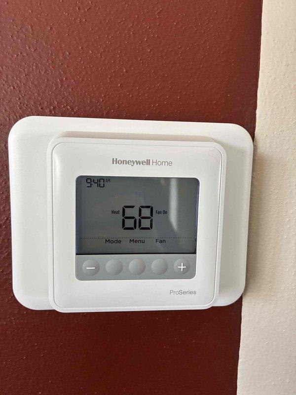 Inspected and serviced Carrier furnace system located in utility area. Verified proper installation of PVC ventilation components, refrigerant lines with filter drier, and all electrical connections. Confirmed Honeywell ProSeries thermostat functioning correctly with heat mode operational and displaying proper temperature (68°F).