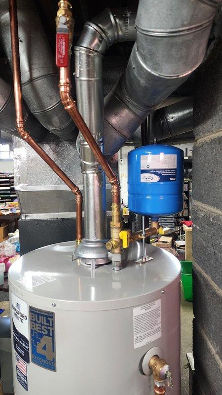 Successfully installed a new water heater system with proper copper supply line connections and galvanized metal ventilation ductwork. Mounted expansion tank on adjacent wall and installed all required valves and fittings to ensure code-compliant operation.