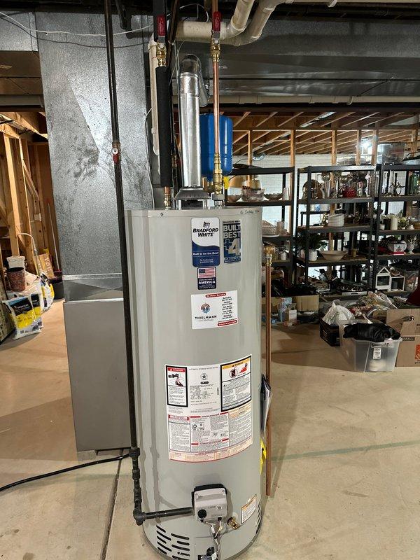 Installed new residential water heater in basement utility area, including proper connection of copper supply lines, installation of expansion tank, and connection to existing metal exhaust vent system. Ensured all plumbing connections were secure and properly fitted alongside the existing Carrier furnace system.