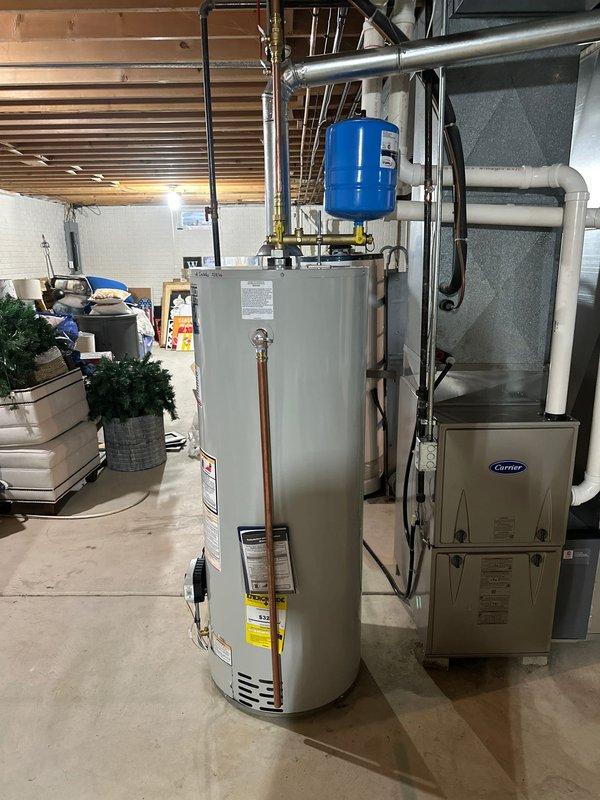 Installed new residential water heater in basement utility area, including proper connection of copper supply lines, installation of expansion tank, and connection to existing metal exhaust vent system. Ensured all plumbing connections were secure and properly fitted alongside the existing Carrier furnace system.