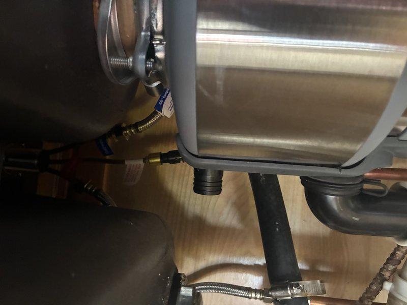 Conducted inspection of kitchen/bathroom sink fixture and under-sink plumbing connections. Examined existing faucet assembly with chrome finish mounted on wooden countertop. Inspected connection points of supply lines to verify proper installation and function of flexible braided stainless steel hoses. Documented condition of all visible plumbing components including brass/copper fittings and water line connections.