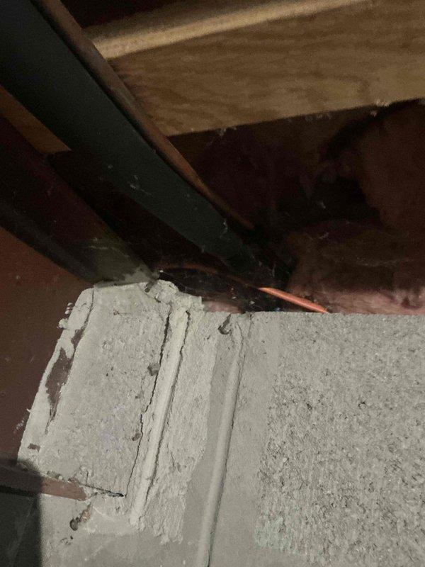 Conducted inspection of aging HVAC system in unfinished basement, documenting deteriorated ductwork, exposed wiring, and significant cobweb accumulation indicating poor airflow. Recommended complete system replacement due to observed inefficiencies, including compromised connections between concrete foundation and wooden joists where copper line set shows signs of wear.