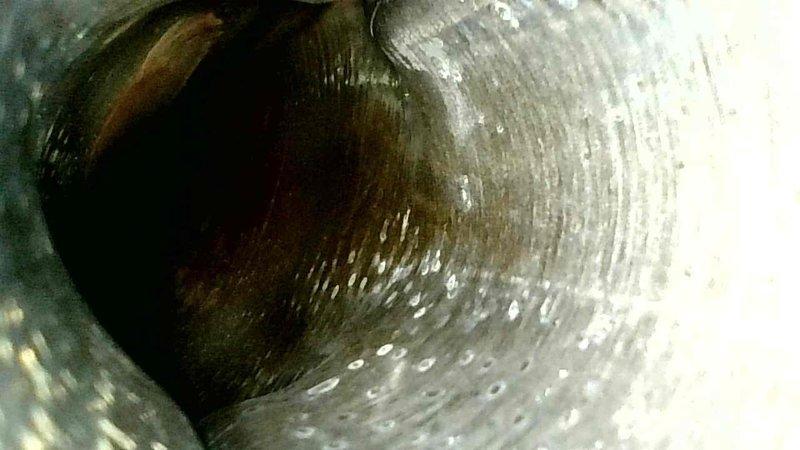 Performed interior duct inspection, revealing accumulated dust and residue buildup within the spiral-wound ductwork. Documented evidence of corrosion and possible moisture issues as indicated by surface discoloration and condensation on metal surfaces.