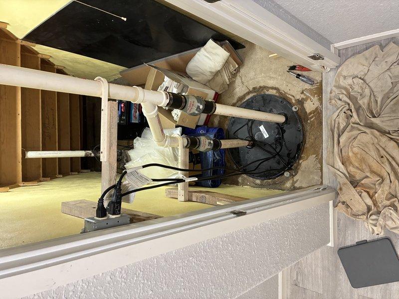 Replaced corroded sump pump system in basement utility area, removing old unit with accumulated sediment and debris from basin. Installed new blue pump unit with complete PVC discharge piping assembly including necessary valves and connectors, and established proper electrical connections to ensure reliable water removal functionality.