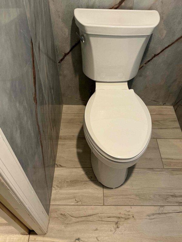 Completed installation of a standard two-piece porcelain toilet in bathroom corner with proper mounting and connection to existing plumbing system. Ensured proper water supply connection and verified leak-free operation after installation. Work area was left clean with all tools and materials removed from the premises.