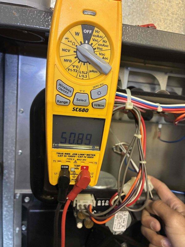 Performed scheduled HVAC maintenance service including electrical diagnostic testing with multimeter, checking system voltage readings (measured 50.89V), and verifying thermostat functionality. Confirmed Sensi thermostat was operating correctly in heating mode, maintaining 66°F ambient temperature with 40% humidity and temporary setpoint of 67°F. System is functioning within normal parameters with all connections secure.