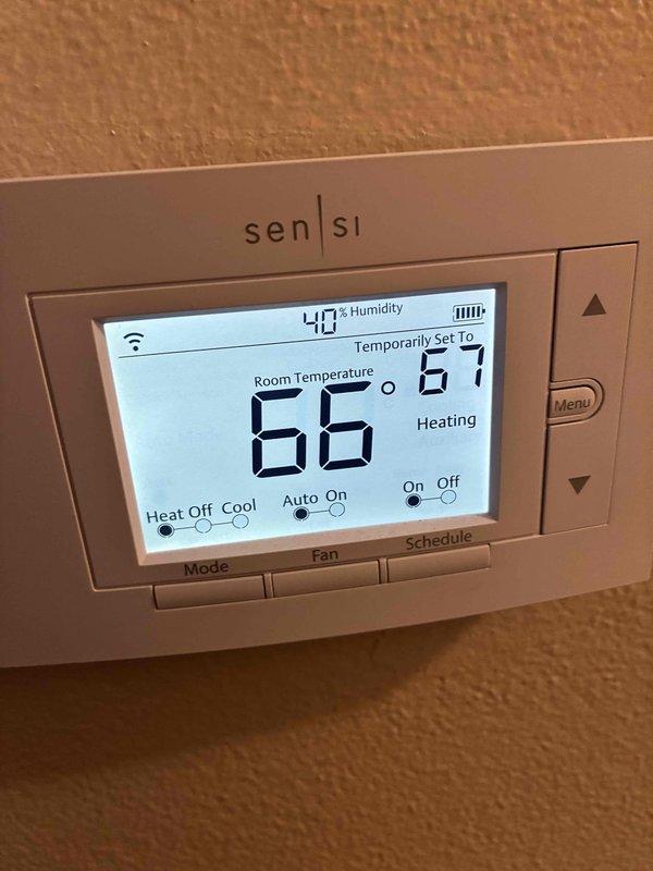 Performed scheduled HVAC maintenance service including electrical diagnostic testing with multimeter, checking system voltage readings (measured 50.89V), and verifying thermostat functionality. Confirmed Sensi thermostat was operating correctly in heating mode, maintaining 66°F ambient temperature with 40% humidity and temporary setpoint of 67°F. System is functioning within normal parameters with all connections secure.
