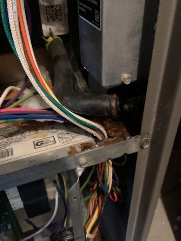 Performed diagnostic inspection on aging furnace system, revealing multiple signs of corrosion and oxidation on the base panel. Examined electrical connections and control board, noting bundled wiring (white, green, orange, yellow, red, and blue) appeared intact despite unit age. Documented interior components and mechanical connections for maintenance planning purposes.