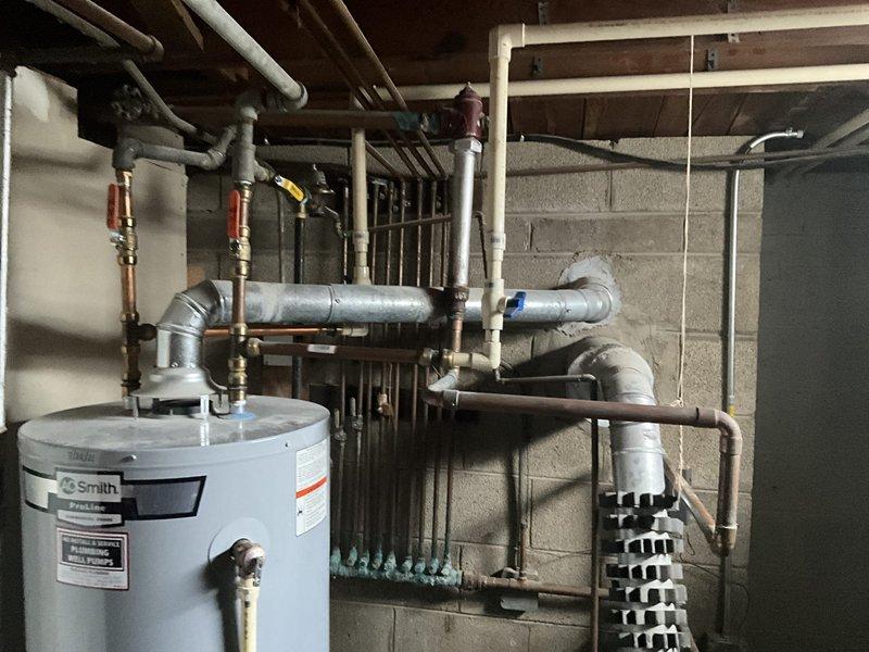 Conducted a comprehensive inspection of an A.O. Smith water heater system and adjacent blue furnace/boiler unit in the basement utility room. Both units appear properly installed with intact connections to copper, galvanized, and PVC piping infrastructure. Documented the current condition of all equipment and plumbing connections for replacement estimate purposes.