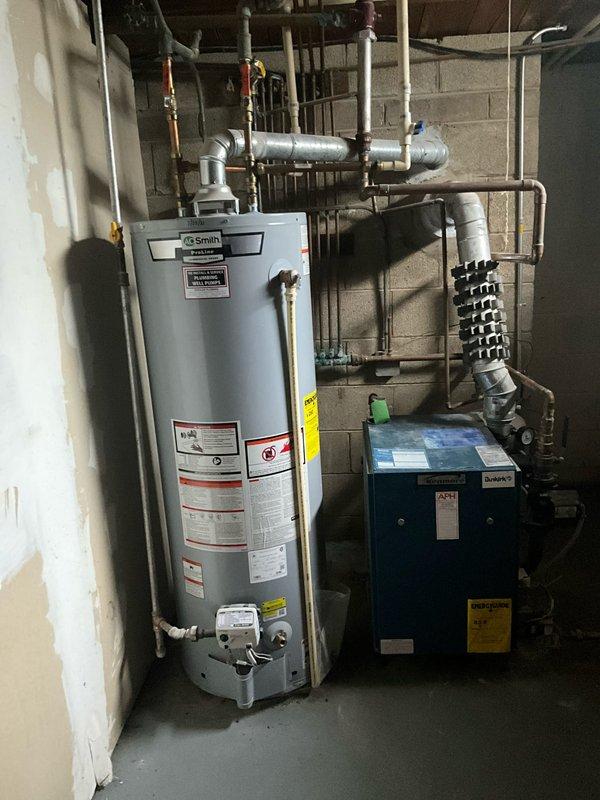 Conducted a comprehensive inspection of an A.O. Smith water heater system and adjacent blue furnace/boiler unit in the basement utility room. Both units appear properly installed with intact connections to copper, galvanized, and PVC piping infrastructure. Documented the current condition of all equipment and plumbing connections for replacement estimate purposes.