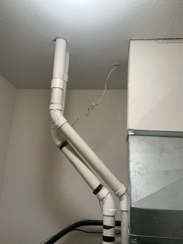 Installed new PVC drainage system for HVAC condensate line with proper labeling and secured connections. System includes vertical runs with appropriate elbows and joints, connecting to existing ductwork. All components were installed to code with necessary support brackets and insulation bands at connection points.