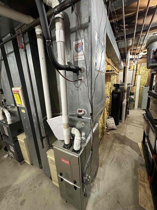 Conducted assessment of Bryant HVAC system for replacement. Exterior inspection revealed snow-covered condenser unit with protective cover installed. Interior inspection of basement mechanical room showed aging furnace with connected PVC ventilation pipes, visible ductwork, and associated components requiring upgrade.