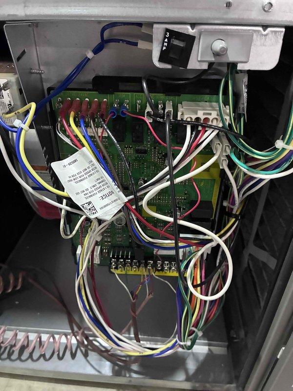 Performed diagnostic inspection of control board in HVAC system following installation callback. Inspected terminal connections and wiring configuration on the main circuit board, focusing on the relay components and 24VAC control circuit. Verified proper wire terminations at DRIVE-24VAC, HUM, ACC, and LINE XFMR CTR connection points to ensure proper system operation.
