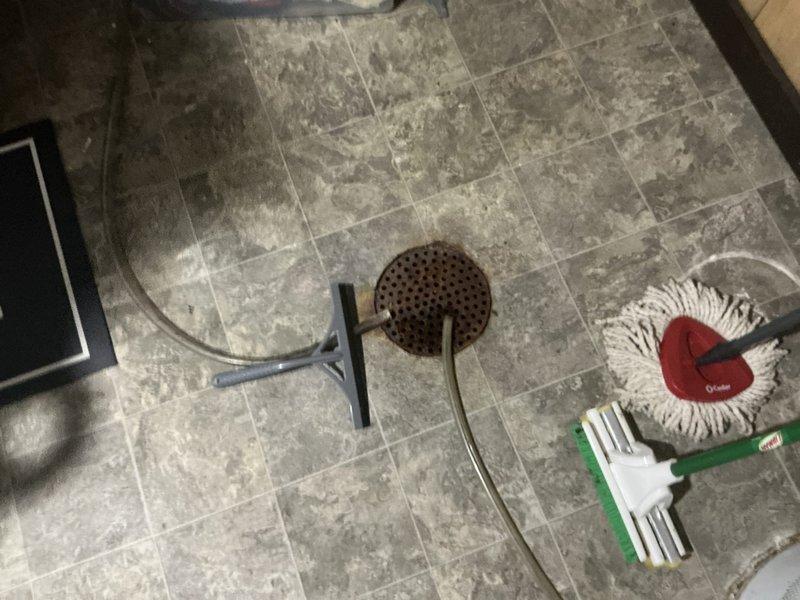 Performed assessment of aging Carrier natural gas HVAC system showing significant wear and dirt accumulation. Documented drain area and surrounding floor condition with visible cleaning tools in place. Recommended complete system replacement based on equipment age, visible deterioration, and operational specifications noted on manufacturer information plate.