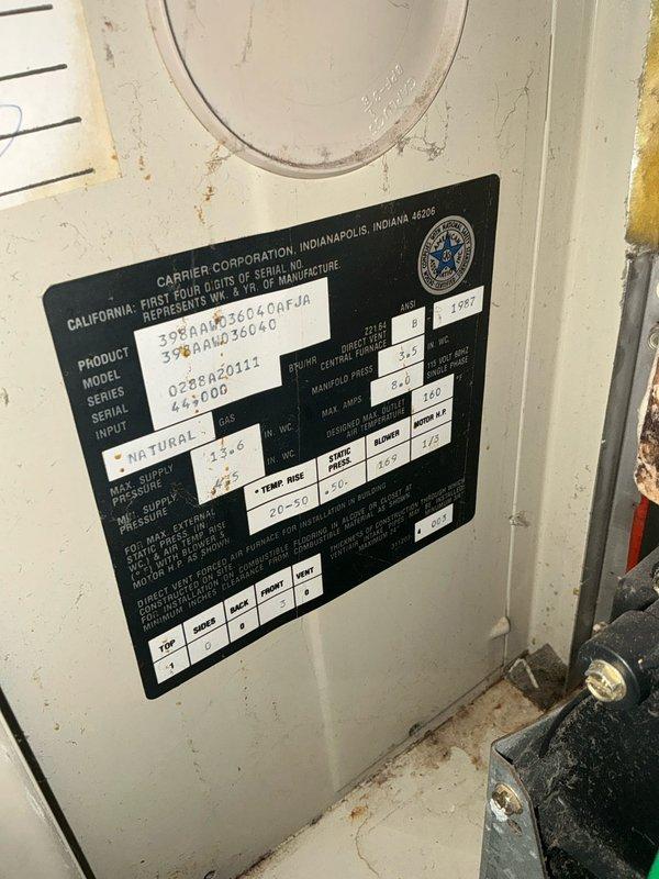Performed assessment of aging Carrier natural gas HVAC system showing significant wear and dirt accumulation. Documented drain area and surrounding floor condition with visible cleaning tools in place. Recommended complete system replacement based on equipment age, visible deterioration, and operational specifications noted on manufacturer information plate.