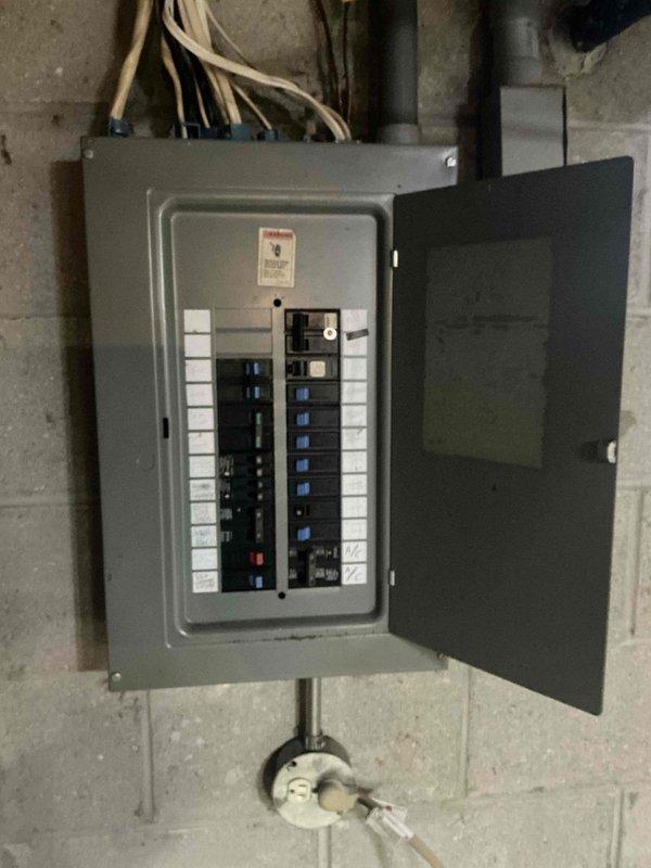 Conducted an assessment of electrical panel and basement utility area for HVAC replacement. Documented existing electrical service panel with multiple circuit breakers to determine available capacity for new system. Noted water damage on concrete floor and existing plumbing infrastructure that will need consideration during installation of replacement HVAC equipment.