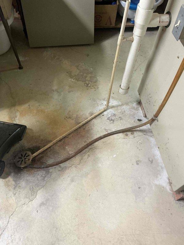 Conducted an assessment of electrical panel and basement utility area for HVAC replacement. Documented existing electrical service panel with multiple circuit breakers to determine available capacity for new system. Noted water damage on concrete floor and existing plumbing infrastructure that will need consideration during installation of replacement HVAC equipment.