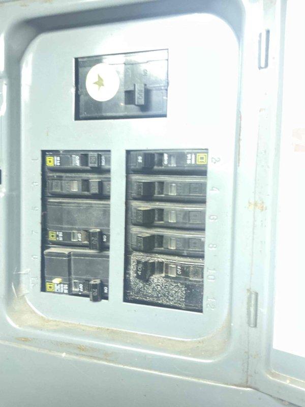 Inspected electrical panel during water heater estimate and observed significant damage to a circuit breaker in the lower right section, showing burn marks and melting. Documented condition of the panel with photos, noting that the damaged breaker will need replacement prior to water heater installation to ensure safe electrical connection.