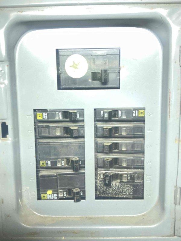 Inspected electrical panel during water heater estimate and observed significant damage to a circuit breaker in the lower right section, showing burn marks and melting. Documented condition of the panel with photos, noting that the damaged breaker will need replacement prior to water heater installation to ensure safe electrical connection.