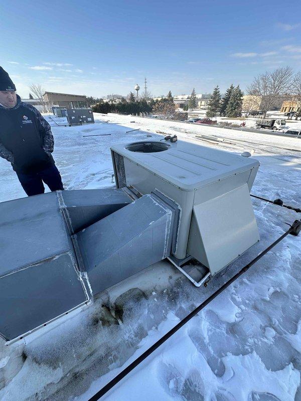 Performed winter inspection of rooftop HVAC unit on commercial building with significant snow accumulation. Accessed equipment panels to evaluate system condition and replacement requirements. Documented current installation configuration and surrounding rooftop conditions to prepare comprehensive replacement estimate.