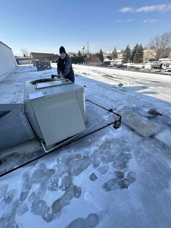 Performed winter inspection of rooftop HVAC unit on commercial building with significant snow accumulation. Accessed equipment panels to evaluate system condition and replacement requirements. Documented current installation configuration and surrounding rooftop conditions to prepare comprehensive replacement estimate.
