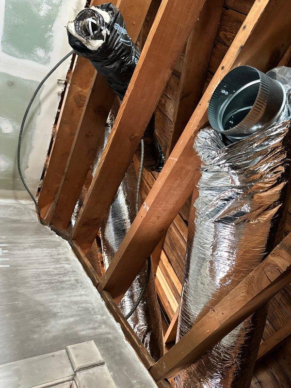 Installed new insulated metal ductwork in attic and wall cavity, properly securing and connecting the system through existing structural framing. Ensured all connections were properly sealed and insulated, with special attention to the collar joint connection visible in the exposed framework area.