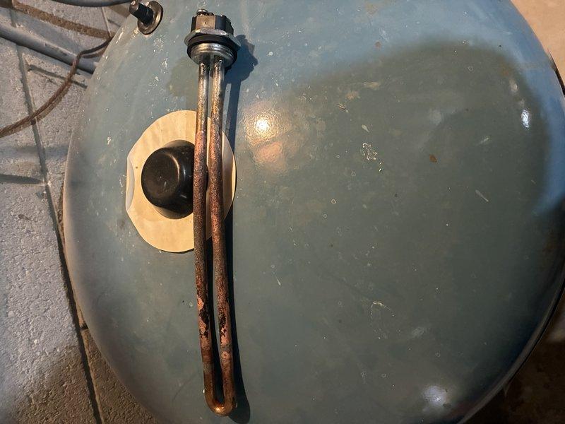 Inspected water heater system and documented significant copper heating element deterioration. Element exhibited advanced corrosion with extensive reddish-brown oxidation throughout, particularly severe at the U-bend section. Photographic documentation was taken to show condition of component requiring replacement due to compromised integrity.