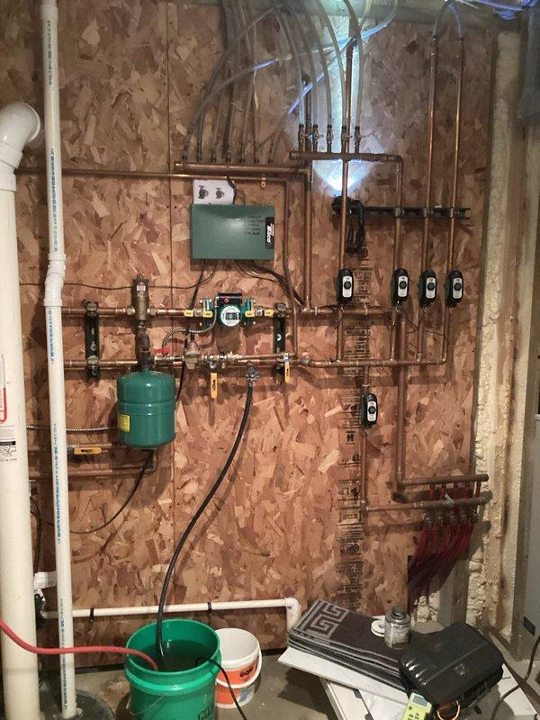 Inspected basement sump pump system and hydronic heating installation. Found water backup issue in sump basin requiring pump replacement. Verified proper operation of expansion tank, zone valves, and pressure gauges on boiler system after service.