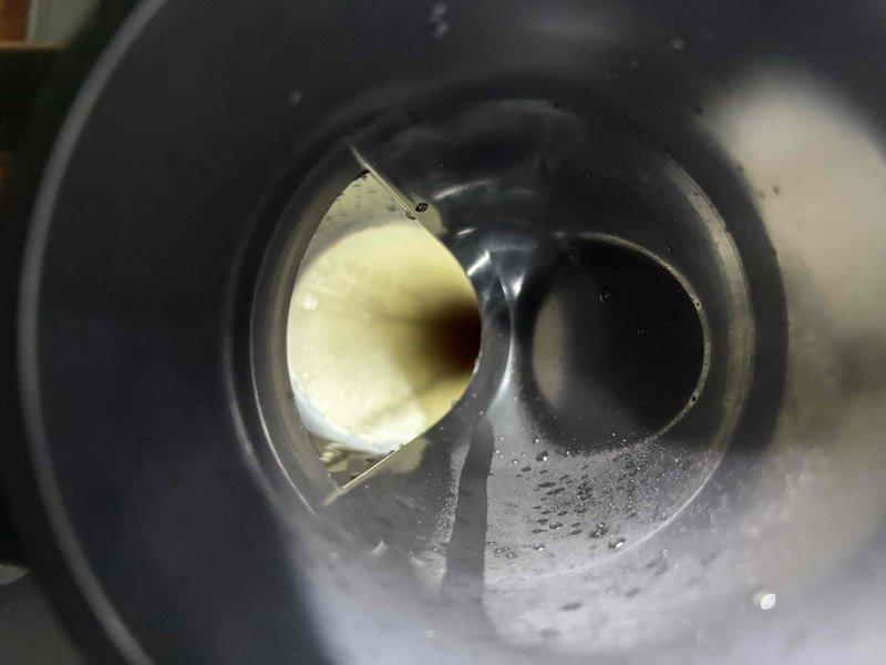 Performed inspection of HVAC system and identified moisture buildup inside cylindrical component with visible water droplets on inner walls. Visual examination revealed a partially obstructed valve/fitting and evidence of condensation issues. Further investigation of connected ductwork showed potential airflow restrictions that may be contributing to system inefficiency.