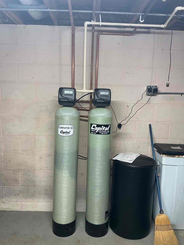 Installed complete water treatment system in basement utility area consisting of three filtration components: a CULTE gray tank, blue tank with electronic control unit, and an Eliminator III Capitol green tank. Connected system to existing copper water supply lines with appropriate valves and fittings. Completed installation of digital control panels and verified proper operation of all treatment components.