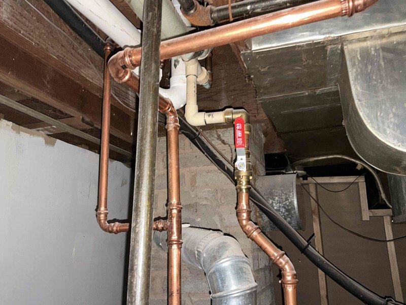 # HVAC Estimate - Replacement Summary

Conducted comprehensive site evaluation for complete HVAC system replacement at residential property. Assessment included exterior condenser unit location with existing electrical service and interior mechanical room containing aged copper piping infrastructure, water heater connections, and ductwork distribution system requiring modernization to accommodate new high-efficiency heating and cooling equipment.

## Detailed Job Description

Performed thorough on-site evaluation for complete HVAC system replacement project. Exterior assessment documented existing condenser pad location adjacent to building foundation with established electrical service infrastructure, including weathered disconnect box and metering equipment mounted on exterior wall. Evaluated ground conditions and mulch bed area for potential equipment placement and clearance requirements per manufacturer specifications.

Interior mechanical room inspection revealed extensive copper 