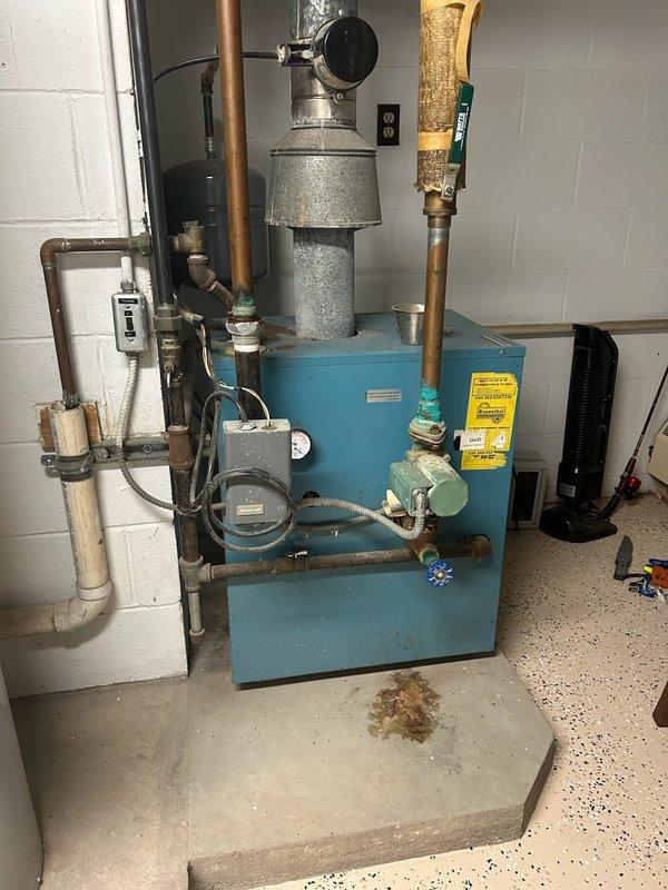 # HVAC Service Report - No Heat Call

## Summary
Responded to no heat call on 10+ year old residential boiler system. Diagnosed and restored heating operation to aging blue cabinet-style boiler unit with associated hydronic components.

## Work Performed

Upon arrival, found customer utilizing portable space heater due to lack of heat from primary system. Conducted comprehensive diagnostic evaluation of hydronic heating system including blue cabinet boiler unit, expansion tank, and associated copper piping network.

Inspected all visible components including:
- Main boiler unit with control panel and electrical switches
- Galvanized expansion tank showing exterior condensation
- Multiple zone valves with blue handles
- Copper supply and return lines with brass fittings
- Pressure relief valve and temperature/pressure gauges
- Electrical control box mounted above unit
- PVC vent piping system

Tested boiler ignition sequence and verified proper operation of limit controls and aquastat. 