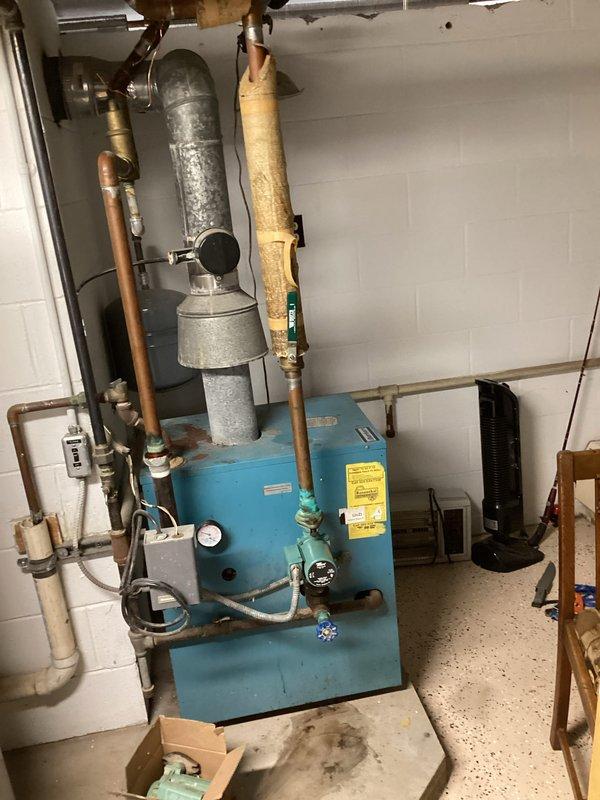 # HVAC Service Report - No Heat Call

## Summary
Responded to no heat call on 10+ year old residential boiler system. Diagnosed and restored heating operation to aging blue cabinet-style boiler unit with associated hydronic components.

## Work Performed

Upon arrival, found customer utilizing portable space heater due to lack of heat from primary system. Conducted comprehensive diagnostic evaluation of hydronic heating system including blue cabinet boiler unit, expansion tank, and associated copper piping network.

Inspected all visible components including:
- Main boiler unit with control panel and electrical switches
- Galvanized expansion tank showing exterior condensation
- Multiple zone valves with blue handles
- Copper supply and return lines with brass fittings
- Pressure relief valve and temperature/pressure gauges
- Electrical control box mounted above unit
- PVC vent piping system

Tested boiler ignition sequence and verified proper operation of limit controls and aquastat. 