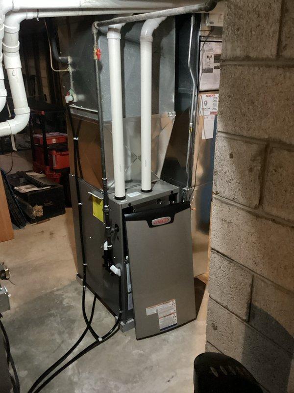# HVAC Install - Furnace Job Summary

Completed installation of new Lennox high-efficiency furnace system in basement utility area. Unit was positioned on concrete floor against foundation wall with proper clearances maintained for service access and code compliance.

## Work Performed

Installed furnace unit with complete venting system utilizing white PVC piping routed through basement ceiling for exhaust and intake air. Venting was properly pitched and terminated according to manufacturer specifications and local building codes. All pipe joints were primed, glued, and secured with appropriate hangers and supports.

Connected refrigerant lines along right side of unit using proper mounting brackets to ensure secure routing and prevent vibration. Lines were insulated where required to prevent condensation and maintain system efficiency.

Completed all electrical connections from furnace to existing power supply, routing wiring along floor and securing to prevent damage. Verified prope