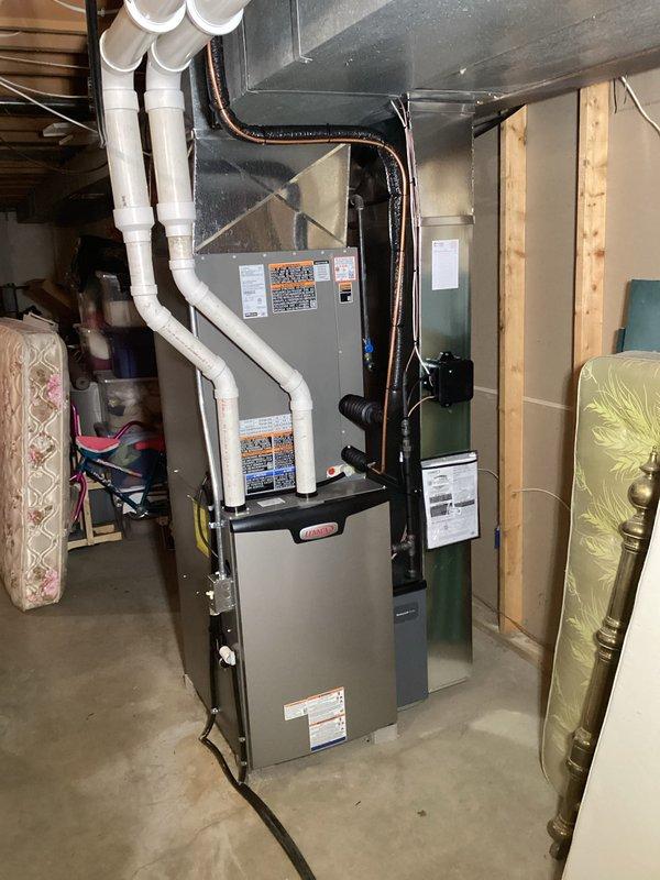 # HVAC Install - Complete System

## Job Description

Completed full HVAC system installation including outdoor condensing unit and indoor furnace. Installed Lennox furnace in basement mechanical room with proper clearances and code-compliant positioning on concrete slab. Routed refrigerant lines through exterior wall penetration, connecting outdoor unit to indoor air handler with appropriate insulation on suction line. Installed condensing unit on level pad between building structures with adequate service clearance. 

Configured PVC condensate drain and intake/exhaust venting from furnace through basement ceiling joists with proper pitch and support. Ran electrical disconnects and control wiring between indoor and outdoor components. Pressure tested refrigerant lines for leaks, evacuated system to proper vacuum levels, and charged unit to manufacturer specifications using calibrated gauges. Verified proper airflow, temperature split, and superheat/subcooling readings. 

System tested