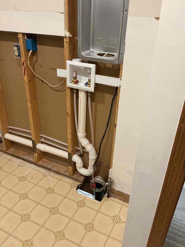 # Plumbing Install - Piping Job Description

Completed installation of white PVC piping system spanning ceiling cavity and interior wall framing. Routed Type CAE/LINE PVC pipe through overhead space above drop ceiling, utilizing proper fittings including T-joints and elbows to achieve required configuration. Secured piping to wooden joists with appropriate hangers and supports to prevent sagging and ensure code compliance.

Installed vertical PVC pipe runs through exposed wall framing, connecting to white plastic junction box housing red and blue valve controls. Configured complex routing pattern with multiple elbows and joints to navigate structural obstacles and achieve proper drainage slope. Integrated piping system through floor penetrations, ensuring proper sealing and support at transition points.

Mounted control valve assembly to wall studs at accessible height for future maintenance and operation. Verified all connections were properly solvent-welded and pressure-tested system