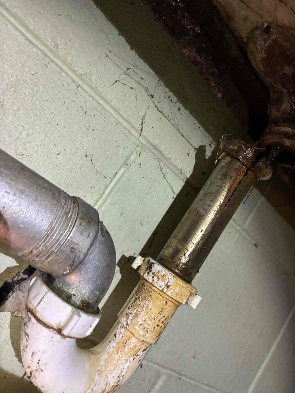 # HVAC Service - Furnace

Performed routine furnace inspection and documented existing building conditions. Photographed exterior structural junction showing weathered components and interior plumbing system with heavily corroded metal piping requiring future attention. Observed rusted heating system pipes with significant oxidation at connection points and brackets, indicating potential replacement needs to prevent system failure.