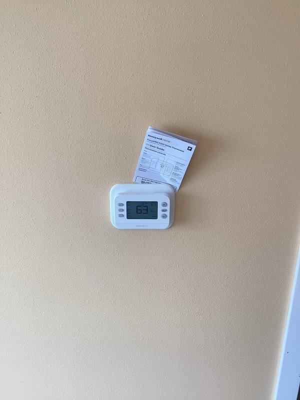 Completed installation warranty service for Honeywell Home FocusPRO P200 programmable thermostat (Model TH2320U1006). Verified proper mounting on wall, confirmed battery installation with alkaline AA batteries, and validated thermostat display functionality showing accurate temperature reading of 63 degrees. Unit tested and operating within manufacturer specifications.