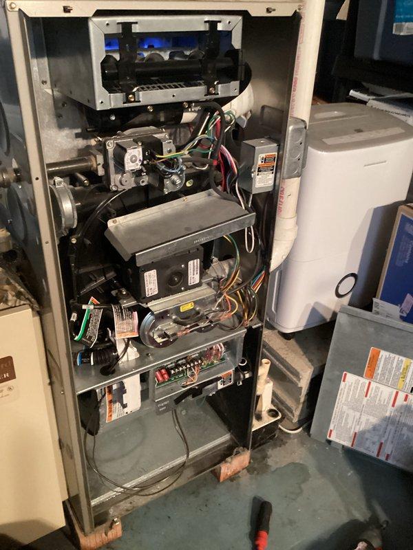 # Furnace Inspection and System Assessment

Performed comprehensive inspection of residential gas furnace system. Removed front access panel to evaluate internal components and operational status. Inspected burner assembly and confirmed proper flame characteristics with visible blue flame pattern indicating complete combustion. Examined gas valve assembly and verified all electrical connections including red, white, green, and black wire terminations were secure and properly seated.

Assessed blower motor assembly housing and internal cabinet components for proper operation and mechanical integrity. Inspected control boards and electronic components throughout the unit, including circuit boards with associated wiring harnesses. Verified all safety labels and specification tags remained legible and properly affixed to respective components.

Evaluated thermostat and humidifier control wiring marked on interior panel. Noted normal dust accumulation consistent with equipment in regular se